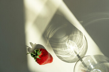 Different glasses for wine, cocktails, drinks, long sun shadow on a light beige background. The concept of wine tasting or summer vacation.