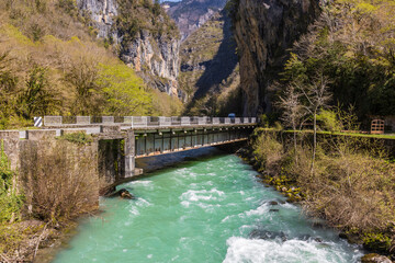 View of the automobile bridge over the Gega mountain river in Abkhazia, Georgia. Landscape with fast turquoise water flow in mountain gorge at sunny springtime day. Road to the in Yupsharsky Canyon