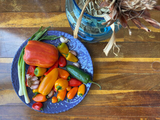 A vibrant collection of different peppers, garlic, and green onions is artistically displayed on a...