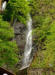 A magnificent waterfall flows over steep, rocky terrain, creating a serene atmosphere with its soothing sound. Vibrant greenery frames the natural wonder, highlighting the beauty of Batumi, Adjara.