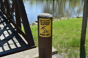 Caution Slippery when Wet Warning Sign for Bike Riders on Bridge