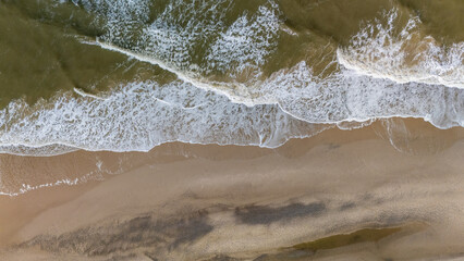 Serene aerial view of Denmarks sandy beach and gentle waves under the midday sun