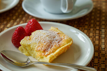 Semolina slice sprinkled with powdered sugar and strawberries for coffee. Close-up