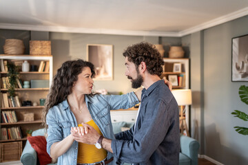 Happy couple dancing together in living room at home