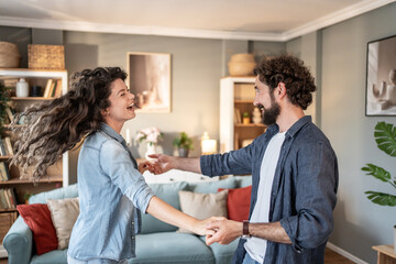 Happy couple dancing and having fun at home in living room