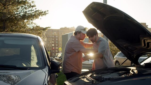Two aggressive drivers are fighting and pushing each other after getting into a car accident. They argue and swear amongst themselves.