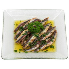 Plate of marinated anchovies garnished with parsley, served on a white dish
