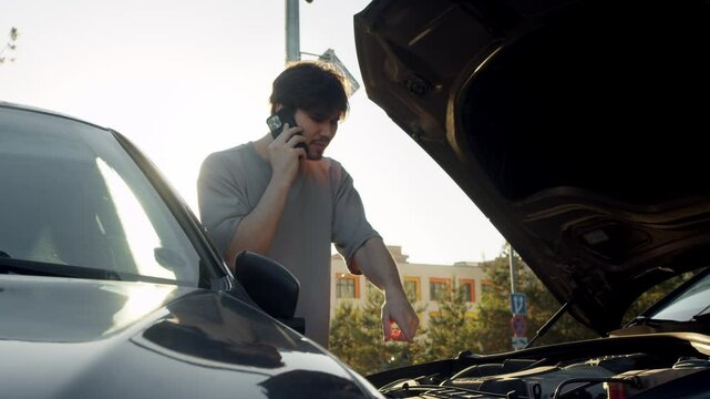 Male driver, clearly agitated, is pacing back and forth next to two cars that were involved in accident. He is on phone with his insurance company explaining situation.