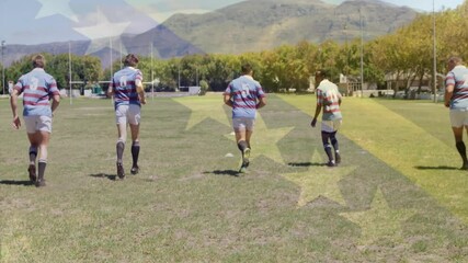 Striped-jersey players bending to pick ball and passing it toward camera on field in rugby drill