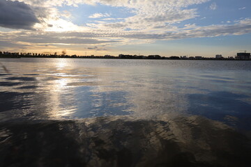 Golden sunlight reflects on tranquil river water under an expansive sky
