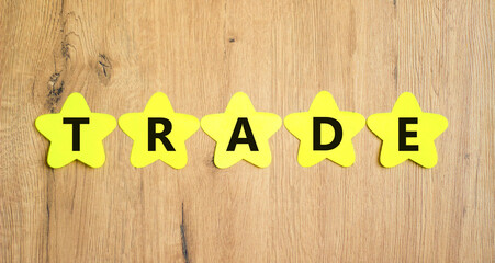 Trade symbol. Concept word Trade on beautiful yellow paper stars. Beautiful wooden table wooden...
