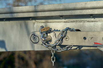 A padlock connects the chain. A metal structure to which a chain and a padlock are attached.