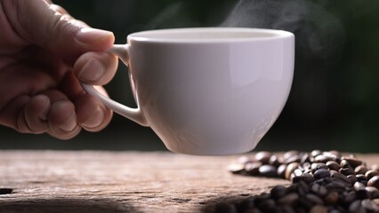 Hand holding a Steaming recycled paper coffee cup with americano coffee green environment close-up viewpoint