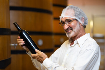 winemaker : winemaker hold bottle of wine check process of make wine. Wooden wine barrels or cognac...