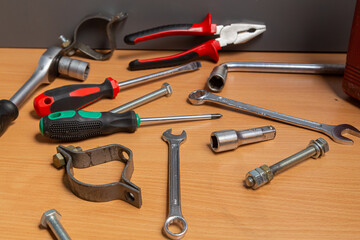 On the table in the workshop there are screwdrivers, wrenches, pliers, nuts and other tools