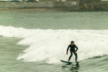 Surfer riding wave on cloudy morning in wetsuit