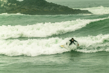 Surfer riding wave in cloudy morning ocean