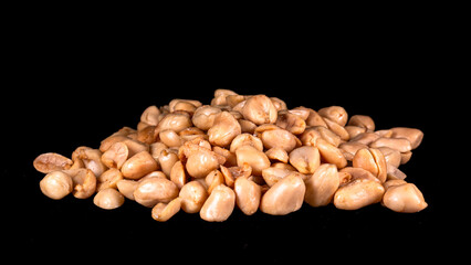 Close-up of a pile of roasted peeled peanuts on a black background. Perfect for culinary, snack, and food ingredient concepts.