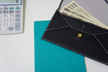 デスク上の電卓と一万円札が入った財布 Calculator and Japanese Yen in Wallet on Desk
