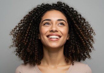 Happy young woman with curly hair looking up