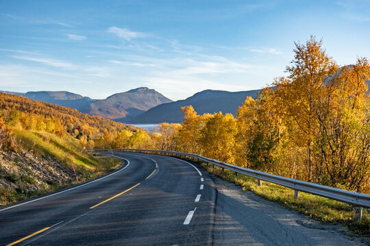 Breathtaking autumn view over Lyngenfjord in Finnmark, Norway. Golden fall foliage illuminates the landscape, inviting scenic drives and unforgettable road trips through the stunning Nordic wilderness
