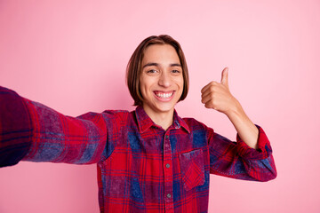 Self portrait of attractive young teen boy making selfie on pink color background