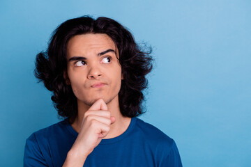 Naklejka premium Portrait of suspicious teenage boy smart person hold arm on chin look side isolated on blue background