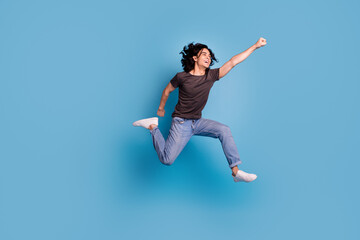 Obraz premium Overjoyed guy jumping over blue studio background