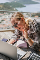 digital nomad woman working remotely from a cozy kitchen during breakfast. Remote work,...