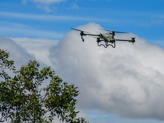 Flying industrial drone over a tea plantation in Nuwara Eliya, Sri Lanka, Asia. Image of an agricultural drone carrying a tank of liquid fertilizer.