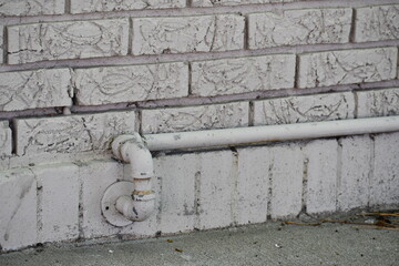 Water pipe sticks out of brick building.