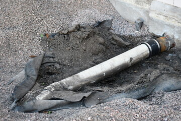 Dug up drain pipe attached to building. Hole dug around pipe.