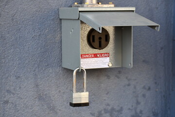 Commercial power outlet. Padlock hangs below. Open to elements. Exterior of building.