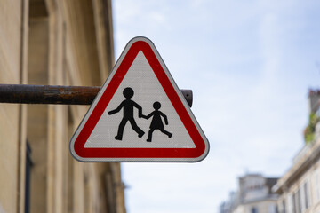 Un panneau triangulaire rouge avertit les conducteurs de la présence de piétons et d'enfants...