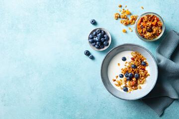 Healthy breakfast. Oat granola with fresh blueberries and milk in a bowl. Blue background. Copy space. Top view.