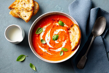 Tomato soup with cream in a white bowl on grey background. Close up. Top view.