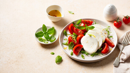 Italian cuisine. Caprese salad with tomatoes, mozzarella cheese and basil. Beige background. Copy space. Close up.