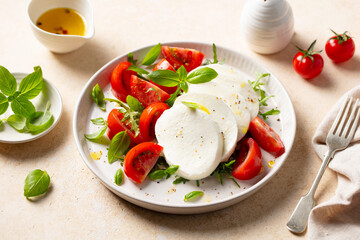 Caprese salad with tomatoes, mozzarella cheese and basil. Beige background. Close up.