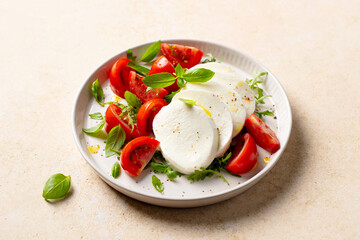 Tomato salad with mozzarella cheese and fresh basil. Caprese salad. Beige background. Close up.