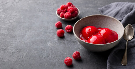 Raspberry ice cream, sorbet, gelato scoops in bowl. Dark grey background. Close up. Copy space.