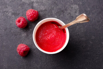 Raspberry sorbet in paper cup. Black stone background. Close up. Top view.
