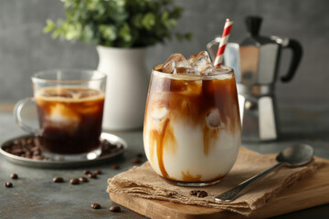 Iced coffee drinks with straw and coffee maker on a wooden board and coffee beans around