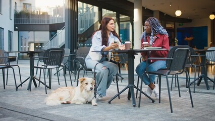 Two women sitting at table of cafe or restaurant. Talking while enjoying cup of hot tea or coffee....