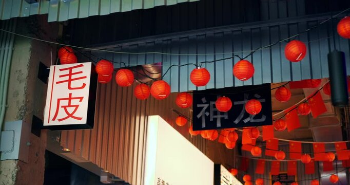 Red paper lanterns with chinese characters hang from a string, swaying gently in the breeze, illuminating the entrance to shen fang, creating a vibrant and festive atmosphere
