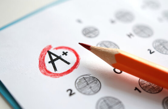 Test answer sheet marked with A grade. Pencil shows great result achievement. School evaluation of excellent academic performance, good student answer. Education concept, exam result.