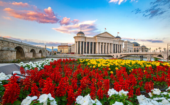 Fototapeta Skopje city center. Colorful flowers in front of the Archaeological Museum. Beautiful spring cityscape of the capital of North Macedonia. View of the Stone Bridge and the Bridge of Arts.