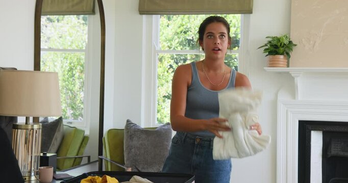 Couple receiving bright tops and folding shirts, sorting shorts into suitcase at home for travel