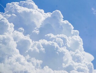 Großes weißes dramatisches Wolkengebilde vor hellblauem Himmel bei Sonne am Nachmittag im Frühling