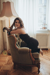 Graceful Woman in Black Dress Posing on Vintage Armchair