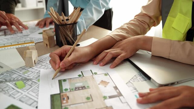 Smart architect and safety engineer discussion about building blueprint on table with architectural document, measurement tools and wooden block scatter around at modern office. Closeup. Delineation.